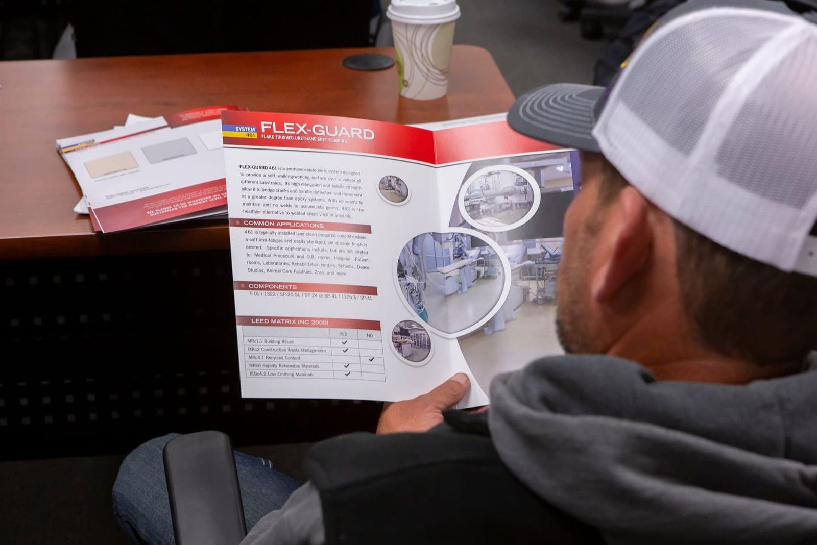 Session attendee reading a Polymer Nation system brochure at the training table